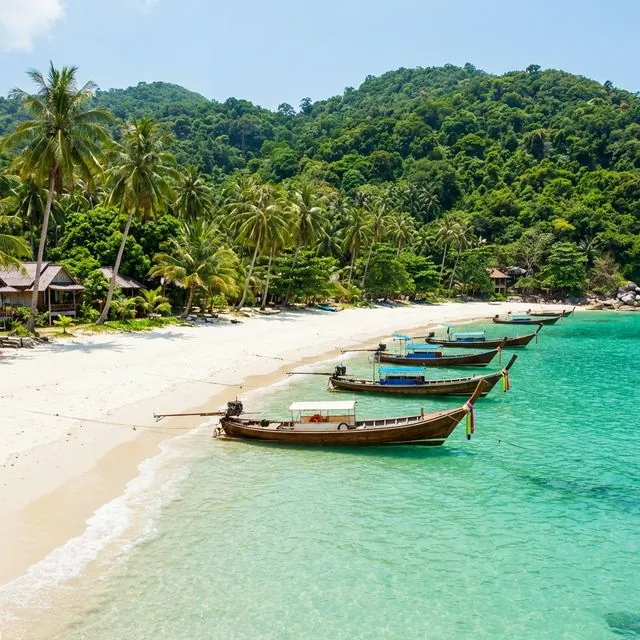 Pristine white sand Bottle Beach with longtail boats and jungle hills